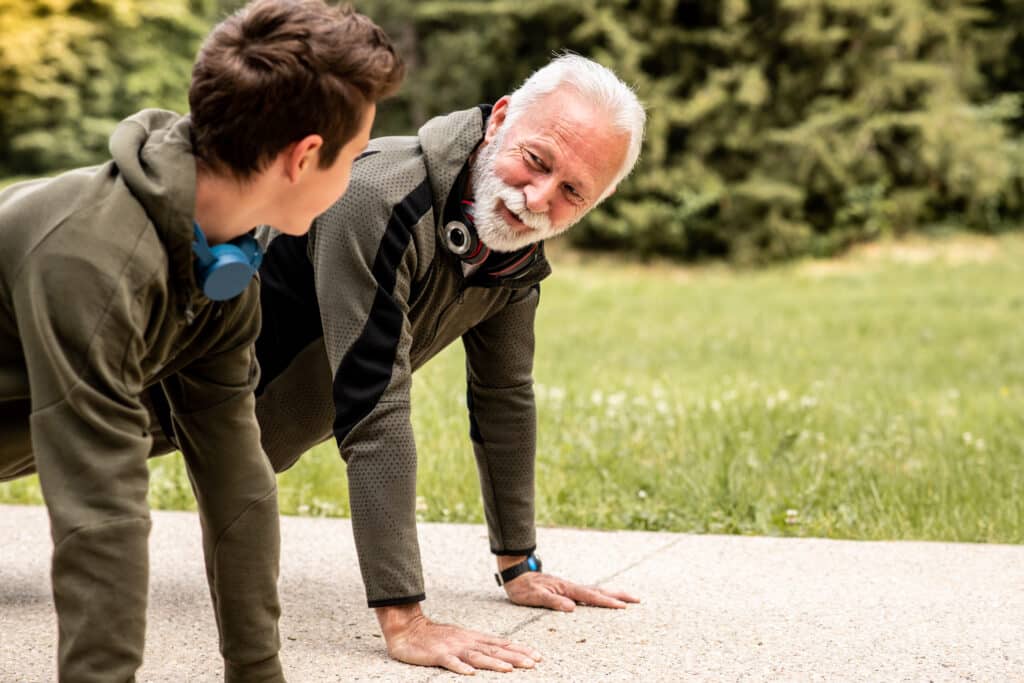 Senior beim Outdoor-Fitnesstraining mit Trainer im Park
